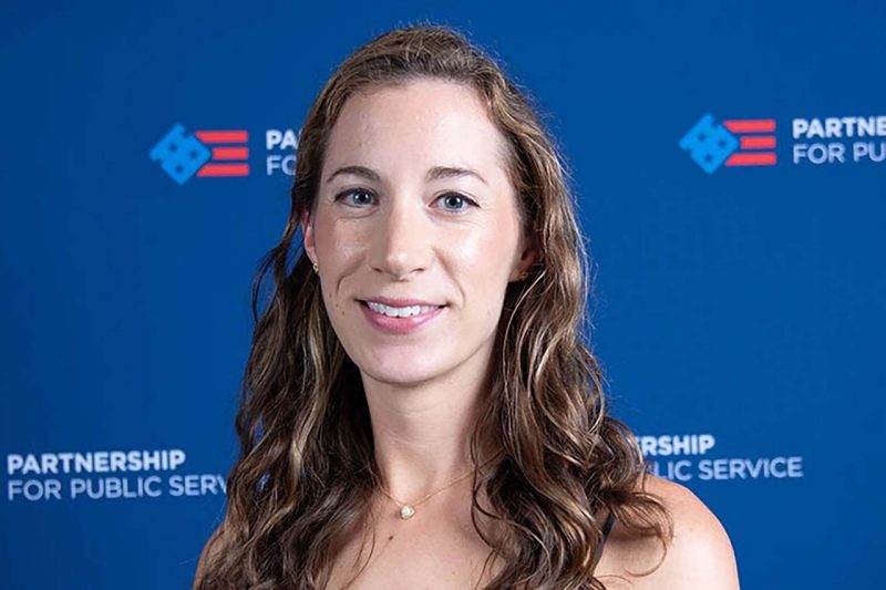 A headshot of Lydia Carpenter in front of a backdrop for the Partnership for Public Service