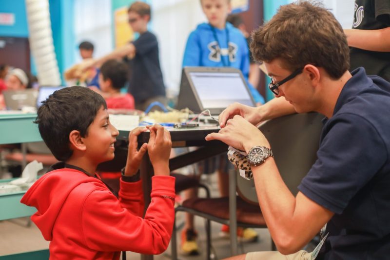 A young student watches in anticipation as a Virginia Tech student helps him with his creation.