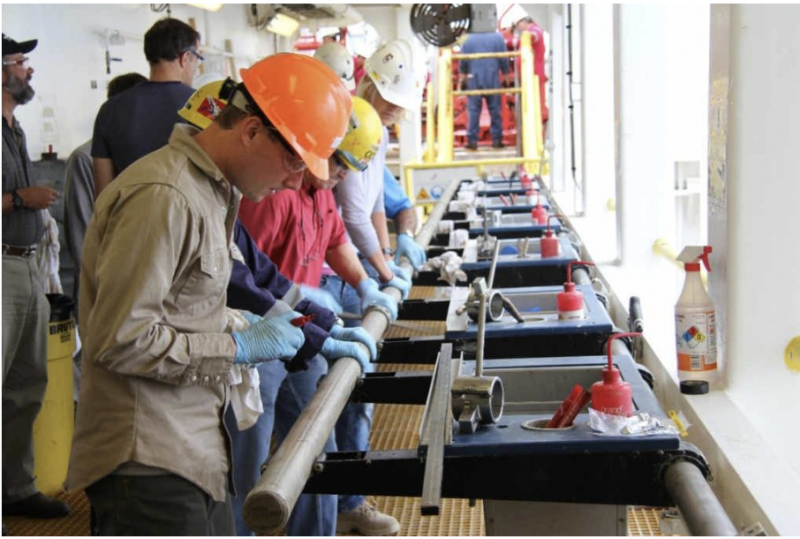 Several workers wearing helmets standing at a production line