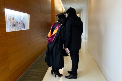 two students huddle before graduation