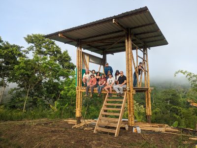 Hauptman's team and the Regeneration Field Institute team sit atop the prototype cabin they built together on the Los Arboleros Farm in Chone, Ecuador. 