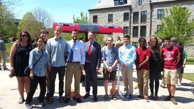 Students posed with President Sands next to a solar charging table